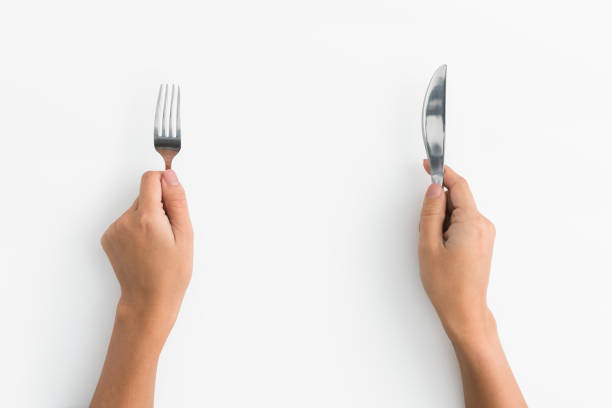 istock Woman hands holding fork and knife on white background 1084491190