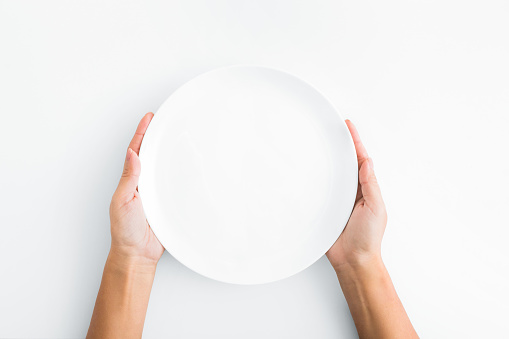 Lunch time. Female hands holding empty plate on white background, top view, copy space