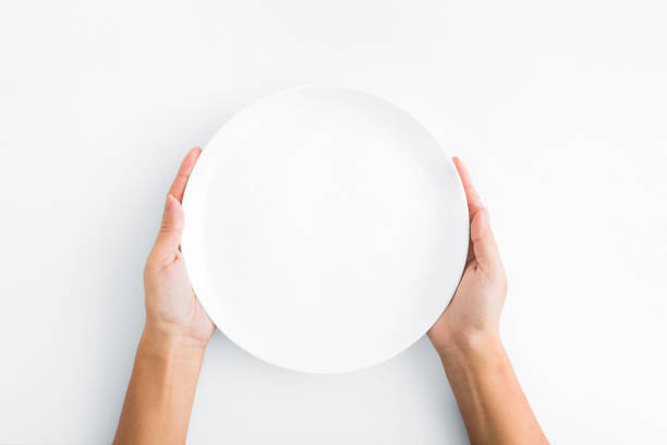 Female hands holding empty plate on white background Lunch time. Female hands holding empty plate on white background, top view, copy space cooking show stock pictures, royalty-free photos & images