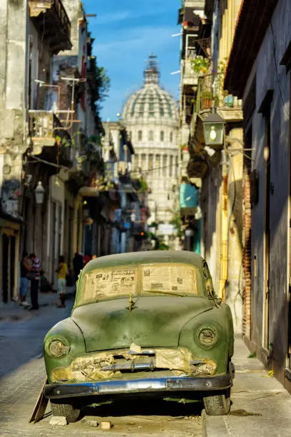 HAVANA, CUBA – MAY 20, 2016: Retro car is on the street of Old Havana. There is a true colour of Cuba. Old buildings, broken pavement and damaged car are the integral parts of cuba