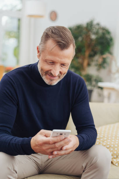 istock Man smiling to himself as he reads a text message 1084515944