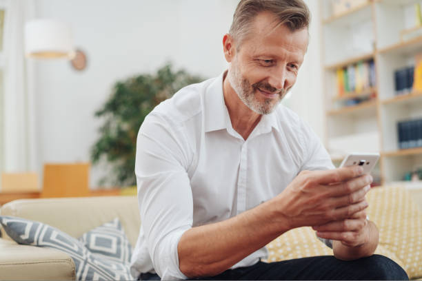 istock Middle-aged man smiling as he reads an sms 1084516938
