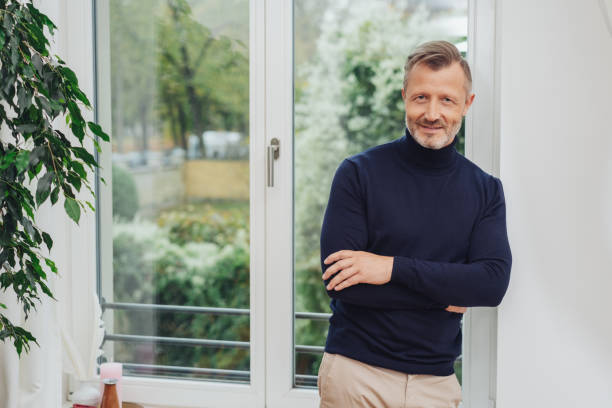 istock Man standing at the window and smiling 1084521314