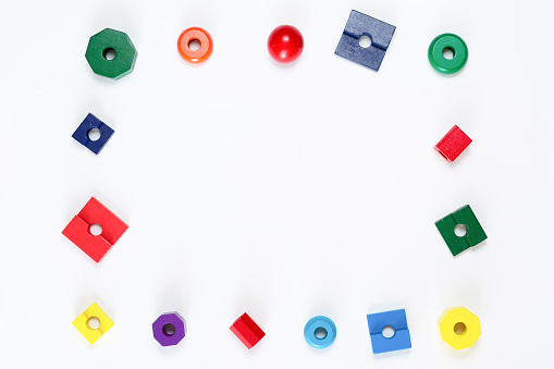 Top view of colorful children toys frame on white background, flat lay. Kids blocks and geometric shapes with copy space