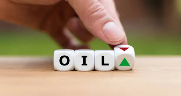 Hand is turning a dice and changes the direction of an arrow symbolizing that the Oil price is changing the trend and goes down instead of up (or vice versa)