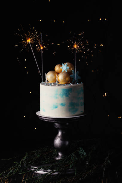 istock Decorated Christmas cream cake, burning sparkler on dark background 1084531684