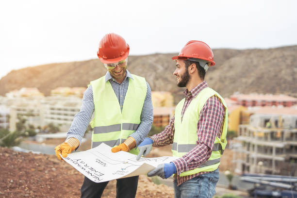 istock Workers engineers discussing about the new building area - Young builders reading the project in the construction site - Teamwork, carpentry, engineering concept 1084532964