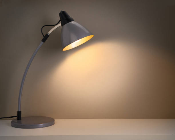 istock Switched on vintage or retro desk lamp on white table 1084534018