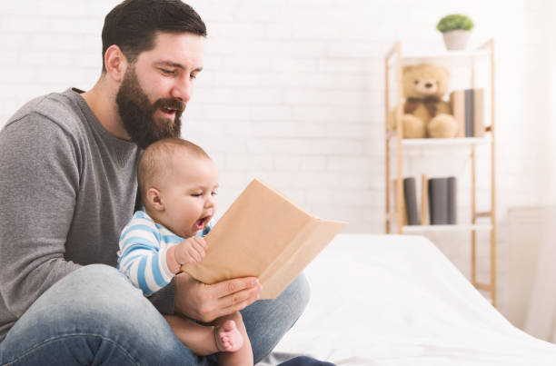 Father reading book to little baby son