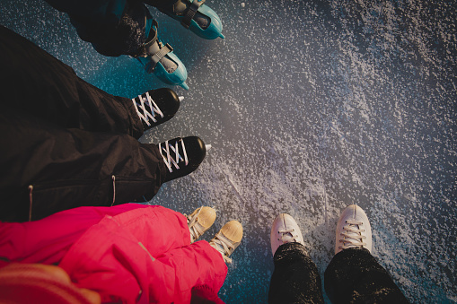 active family- mom, dad and kids skating in winter snow