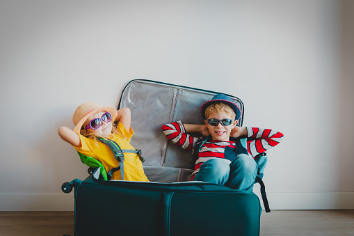 happy kids -boy and girl- enjoy packing and travel, family going on vacation