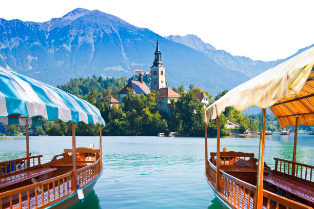 tipiche barche in legno, in sloveno chiamato pletna, nel lago di bled, il lago più famoso della slovenia con l'isola della chiesa (europa - slovenia) - immagine su sfondo bianco per una facile selezione - santa maria church foto e immagini stock