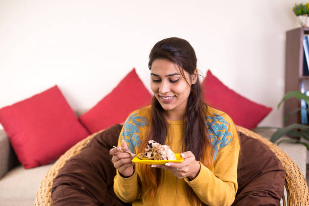 Happy woman eating cake in the living room