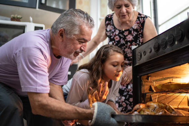 abuelos y nieta comprobando el tradicional pavo para la cena de navidad - al horno fotos fotografías e imágenes de stock