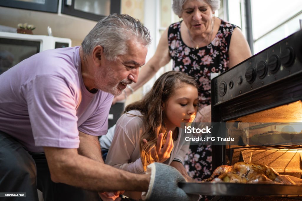 Grandparents and Granddaughter Checking the Traditional Turkey for Christmas Dinner It's Christmas Time Cooking Stock Photo