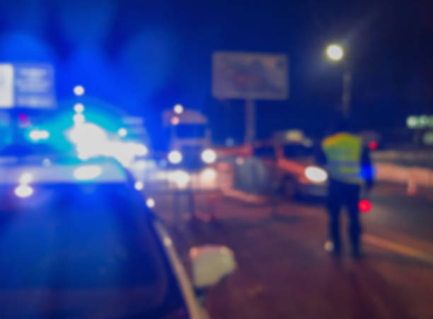 Unrecognizable blurry police car lights and police force officer on night road background, crime scene, night patrolling the city. Abstract  defocused image. stock photo
