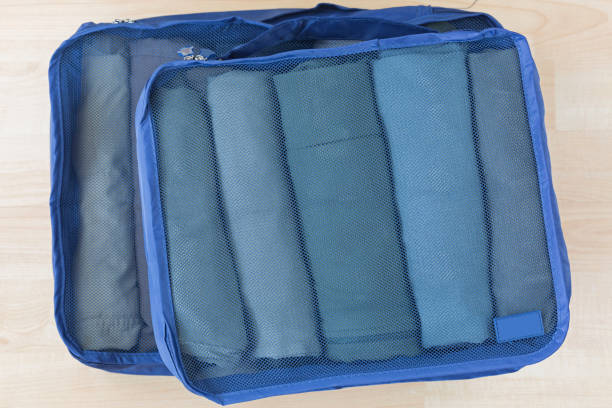 Cube meshed bags with rolled clothes. Set of travel organizer to help packing well organized Cube meshed bags with rolled clothes, t-shirt, pants. Set of travel organizer to help packing luggage easy, well organized cube shape stock pictures, royalty-free photos & images