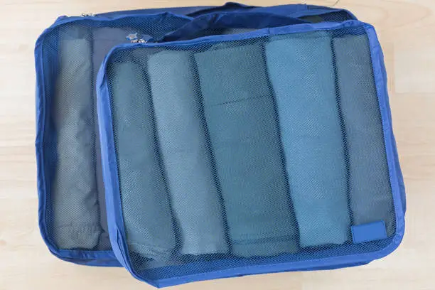 Photo of Cube meshed bags with rolled clothes. Set of travel organizer to help packing well organized