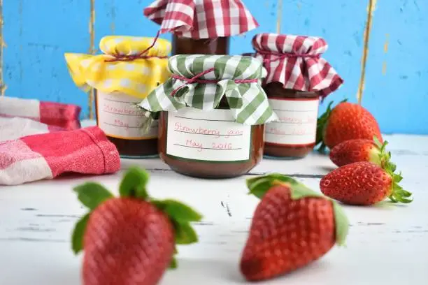 Strawberry jam jars before light blue background
