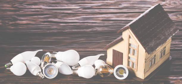 lámparas led se encuentran cerca de la distribución de la casa sobre un fondo de madera - piggy bank savings investment glasses fotografías e imágenes de stock