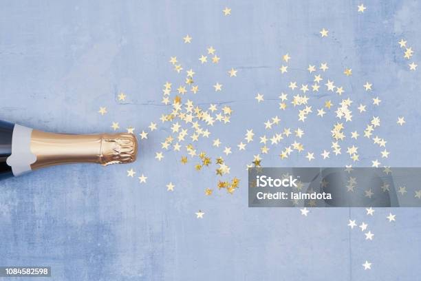 Champagne Bottle With Confetti Stars On Blue Background Holiday Concept Flat Lay Style Copy Space Top View Stock Photo - Download Image Now