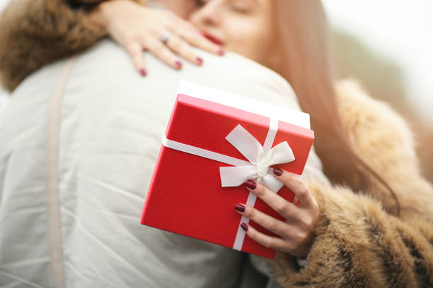 sonriente mujer celebración de día de san valentín regalos y abrazos man - valentine present fotografías e imágenes de stock