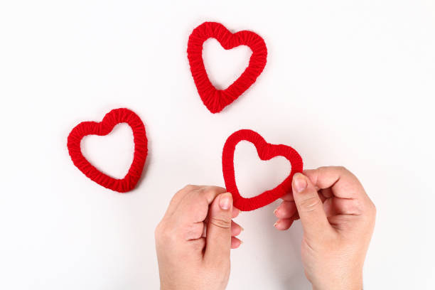 istock Red handmade diy hearts made of cardboard, yarn on a white background. Gift ideas for Valentines Day, day love, concept of February 14. Step by step. process crafts. Valentine card. 1084607724