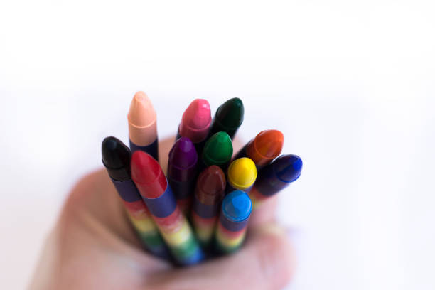 istock Color wax pencils in hand on white background close up 1084609858