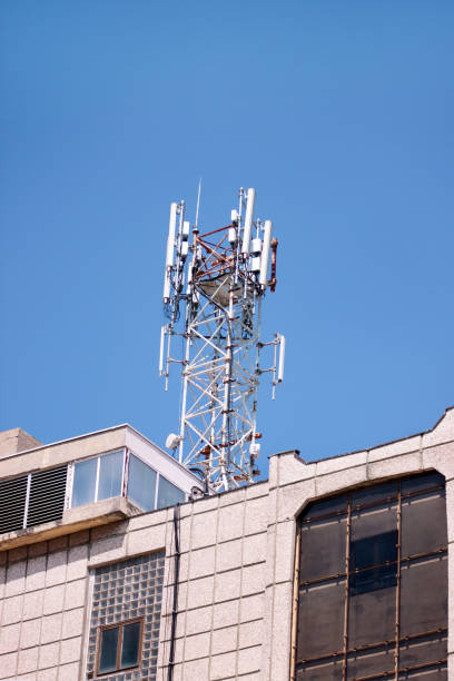 istock Telecommunication base stations network repeaters on the roof of building. The cellular communication aerial on city building roof. Cell phone telecommunication tower. Antennas on top of building. 1084616746
