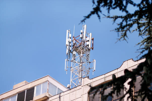 istock Telecommunication base stations network repeaters on the roof of building. The cellular communication aerial on city building roof. Cell phone telecommunication tower. Antennas on top of building. 1084616990