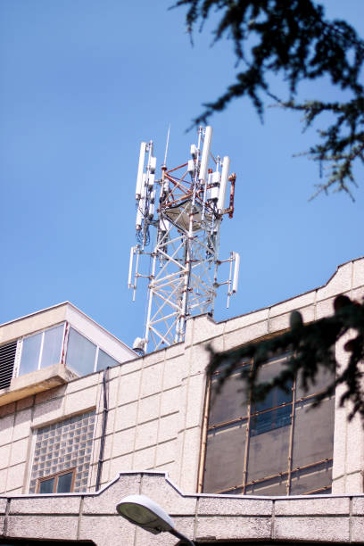 istock Telecommunication base stations network repeaters on the roof of building. The cellular communication aerial on city building roof. Cell phone telecommunication tower. Antennas on top of building. 1084617018