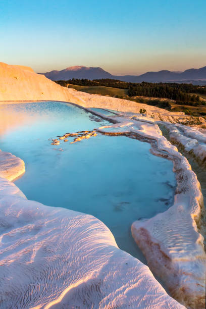 Pools of Pamukkale in Turkey in sunset, contains hot springs and travertines, terraces of carbonate minerals left by the flowing water, UNESCO World Heritage Site stock photo