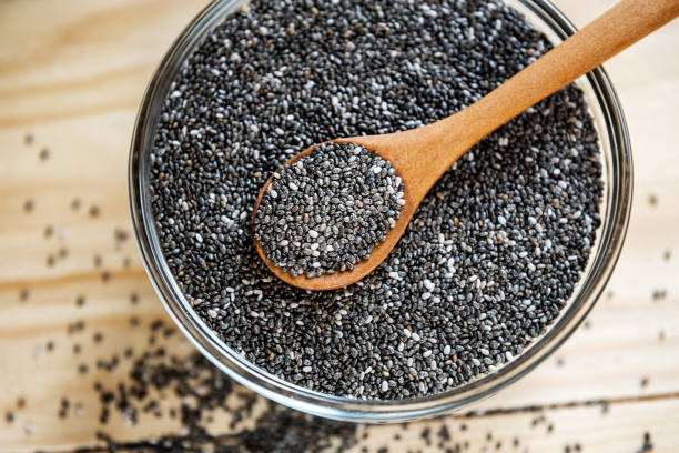Raw organic black chia seeds on wooden spoon