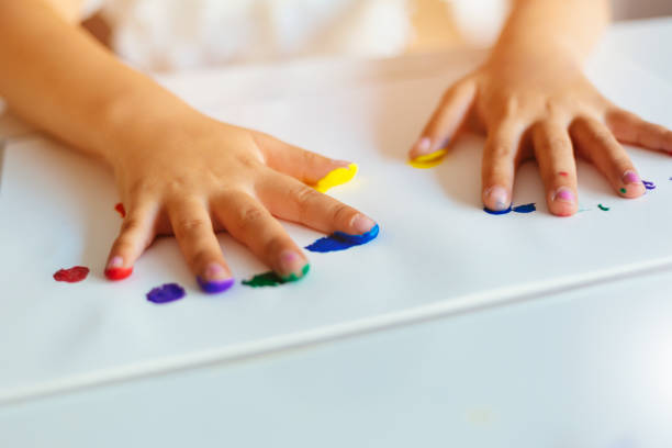 Close-up of colored little girl's hands on paper