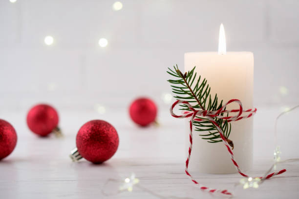istock Christmas home decoration. Burning white candle and Christmas interior red decorations on table 1084668832