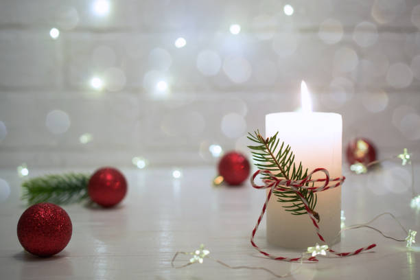 istock Christmas home decoration. Burning white candle and Christmas interior red decorations on table 1084668846
