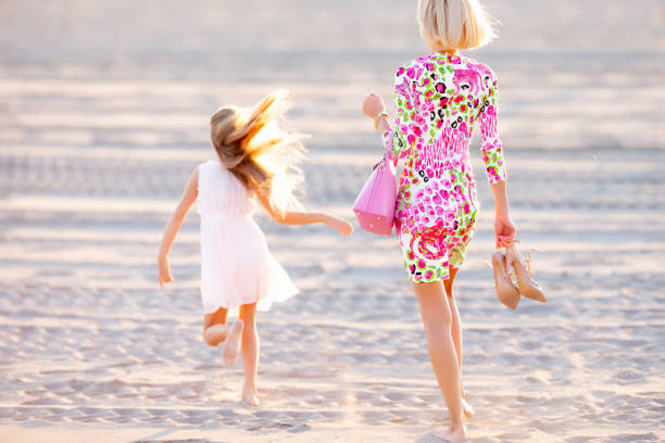 Mother and Daughter Walking and Enjoying on Sandy Beach.