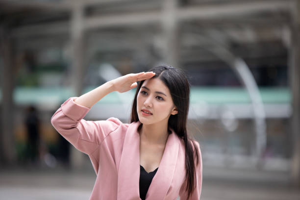 istock Thoughtful Young Businesswoman Shielding Eyes While Standing In City 1084687132
