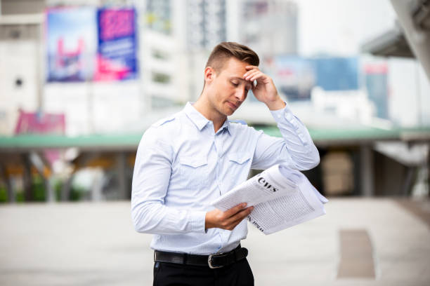 istock Frustrated Businessman Reading Newspaper Against Building 1084687170