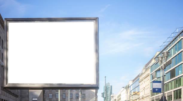 istock Empty billboard for public advertisement on the roadside. Space for text. Blue sky and city background. 1084693596