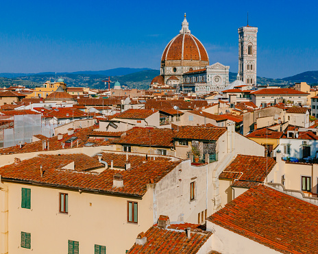 View of the Florence Cathedral and Giotto's Bell Tower under blue sky, over houses of the historical center of Florence, Italy