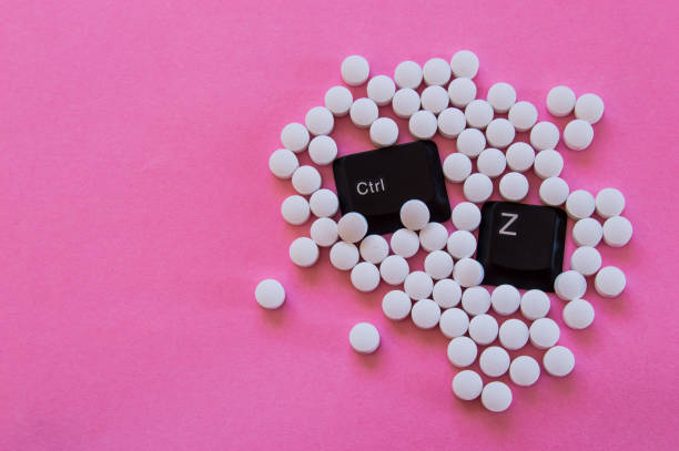 Keys CTRL + Z of a computer keyboard covered by white pills isolated on pink background. Pop photography, concept of undo, addiction or change. Keys CTRL + Z covered by white pills isolated on pink background. Pop photography, concept of undo or change. undo key stock pictures, royalty-free photos & images