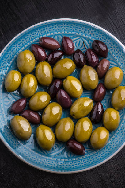 istock Green and dark olives on a blue greek plate. 1084702074