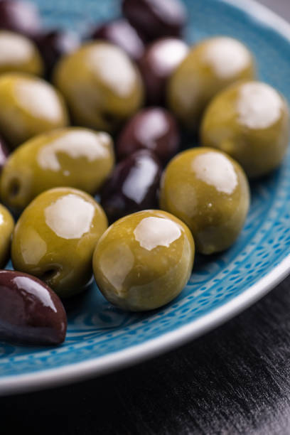 istock Green and dark olives on a blue greek plate. 1084702288