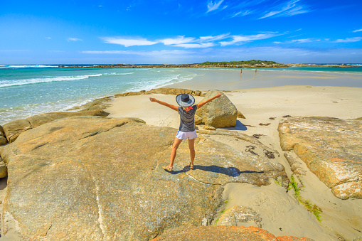 Summer season in Denmark coast. Woman with open arms enjoying on the shore with low tide in Madfish Bay, William Bay National Park, Albany region, Western Australia.