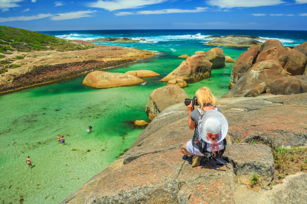 Woman photographer takes shot of Elephant Rocks in William Bay National Park, Denmark, Western Australia. Female traveler takes pictures with professional camera of Great Southern Ocean coastline.
