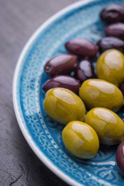 istock Green and dark olives on a blue greek plate. 1084704546