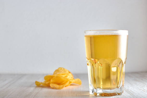 istock a glass of cold, wheat, light beer with chips scattered on the table. copy space. horizontal view on a light background. 1084710632