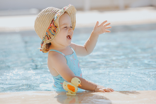 Happy laughing toddler girl having fun in a swimming pool