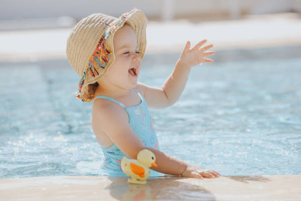счастливый смех малыш девушка весело провести время в бассейне - duck swimming pool animal bird стоковые фото и изображения